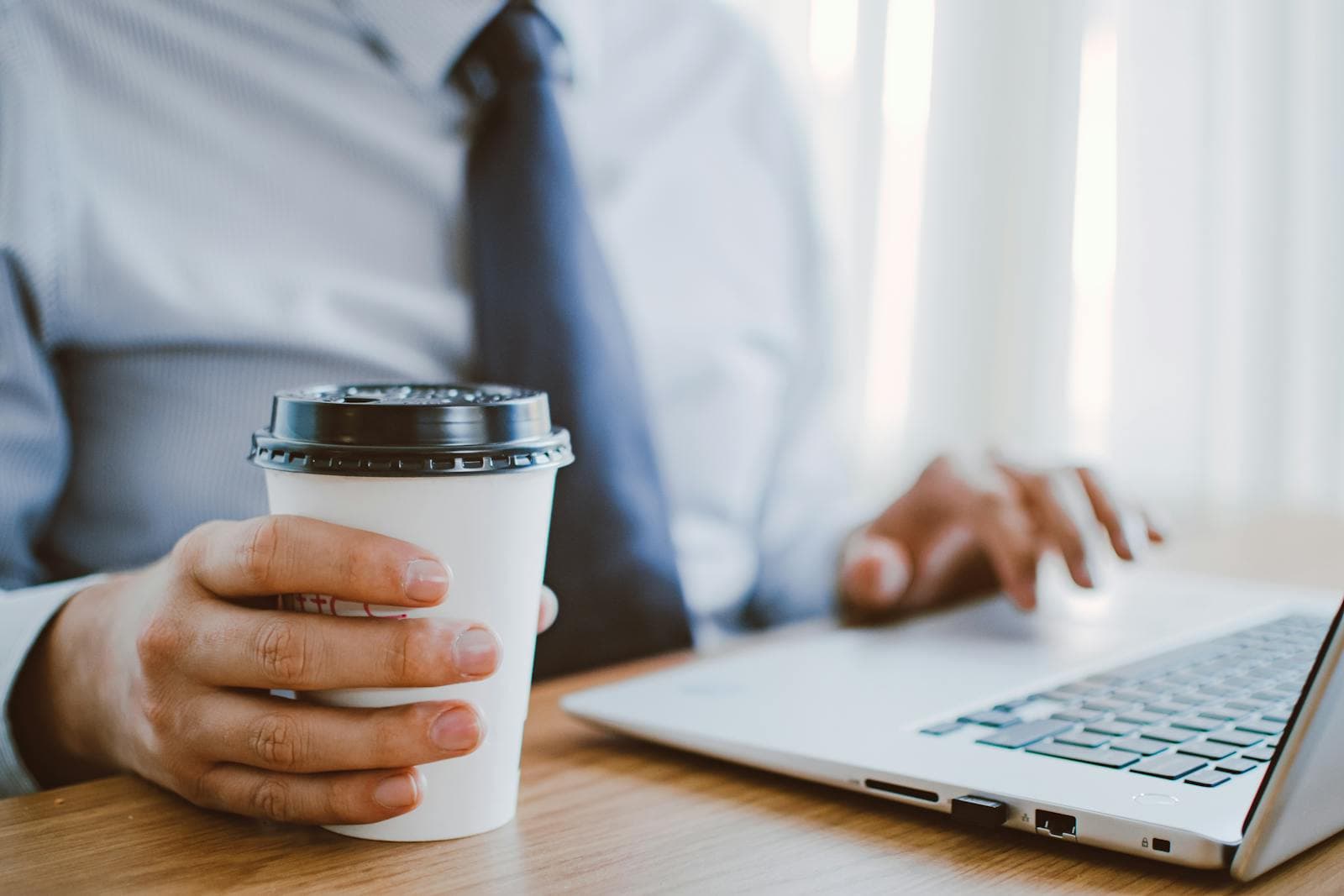 A person working privately on a laptop with a coffee